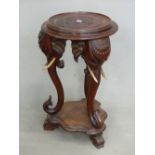 AN ANTIQUE CARVED HARDWOOD EASTERN URN STAND WITH ELEPHANT HEAD SUPPORTS. Dia. 48cm x H. 80cm.