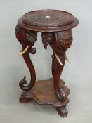 AN ANTIQUE CARVED HARDWOOD EASTERN URN STAND WITH ELEPHANT HEAD SUPPORTS. Dia. 48cm x H. 80cm.