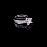 A 14ct WHITE GOLD AND DIAMOND RING. THE CENTRAL DIAMOND A PRINCESS CUT IN A FOUR CLAW CORNER AGAINST