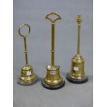 THREE BRASS HANDLE TOPPED DOOR STOPS, THE CAPSTAN AND BELL SHAPED BASES WEIGHTED, THE TALLEST. H