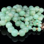 A GRADUATED AND KNOTTED DOUBLE ROW OF JADE BEADS WITH A 9ct GOLD BARREL CLASP GRADUATING FROM 4.