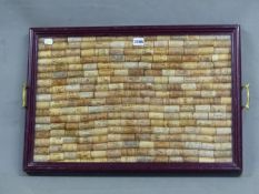 A TWO HANDLED TRAY GLAZED OVER WINE BOTTLE CORKS, THE BROWN PAINTED WOOD FRAME. 63.5 x 44cms.