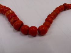 A STRING OF VINTAGE GRADUATED CORAL BEADS, CARVED CORAL EAR CLIPS, AND TWO COSTUME BRACELET.