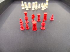 AN ANTIQUE CARVED BONE AND IVORY MINIATURE CHESS BOARD AND PIECES.