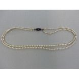 A DOUBLE ROW OF CULTERED PEARLS ON AN 18ct STAMPED WHITE GOLD AND BLACK ONYX CLASP.