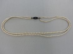 A DOUBLE ROW OF CULTERED PEARLS ON AN 18ct STAMPED WHITE GOLD AND BLACK ONYX CLASP.