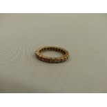 A 9ct GOLD SPINEL SET ETERNITY RING.