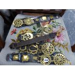 FOUR LEATHER MOUNTED DOUBLE HORSE BRASSES TWO LOOSE AND AND A LEATHER AND BRASS COLLAR.