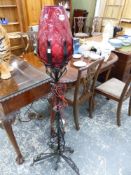 AN UNUSUAL WROUGHT IRON STANDARD LAMP WITH CRANBERRY SHADE.