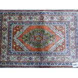 A PERSIAN SILK MAT, THE MEDALLION CENTRAL TO THE TERRACOTTA FIELD AND WHITE GROUND MAIN BORDER. 62 x
