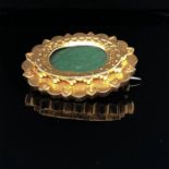 A 15ct GOLD OVAL PANEL BROOCH. A FLARED BORDER WITH A HEART DESIGN FRAMES A GLAZED PERSPEX PANEL