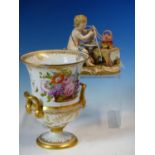 A MEISSEN FIGURE OF A PUTTO SEATED AT A TEA TABLE WHILE A BRAZIER BOILS THE KETTLE, CROSSED SWORDS