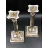 A PAIR OF HALLMARKED WEIGHTED SILVER CORINTHIAN COLUMN CANDLESTICKS ON SQUARE STEP BASES WITH