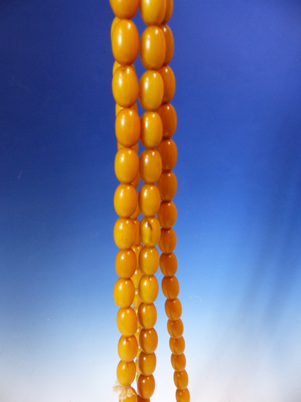 A CONTINUOUS STRING OF 80 UNIFORM OVAL ETHIOPIAN AMBER BEADS WITH KNOT TASSEL PROBABLY FIRST HALF OF - Image 3 of 7