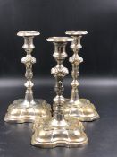 A MATCHED SET OF THREE CONTINENTAL SILVER CANDLESTICKS WITH REMOVABLE DRIP TRAYS, ON SHAPED SQUARE