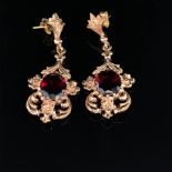 A PAIR OF 9ct GOLD AND GARNET ARTICULATED ORNATE SCROLL WORK DROP EARRINGS WITH PIERCED FITTINGS.