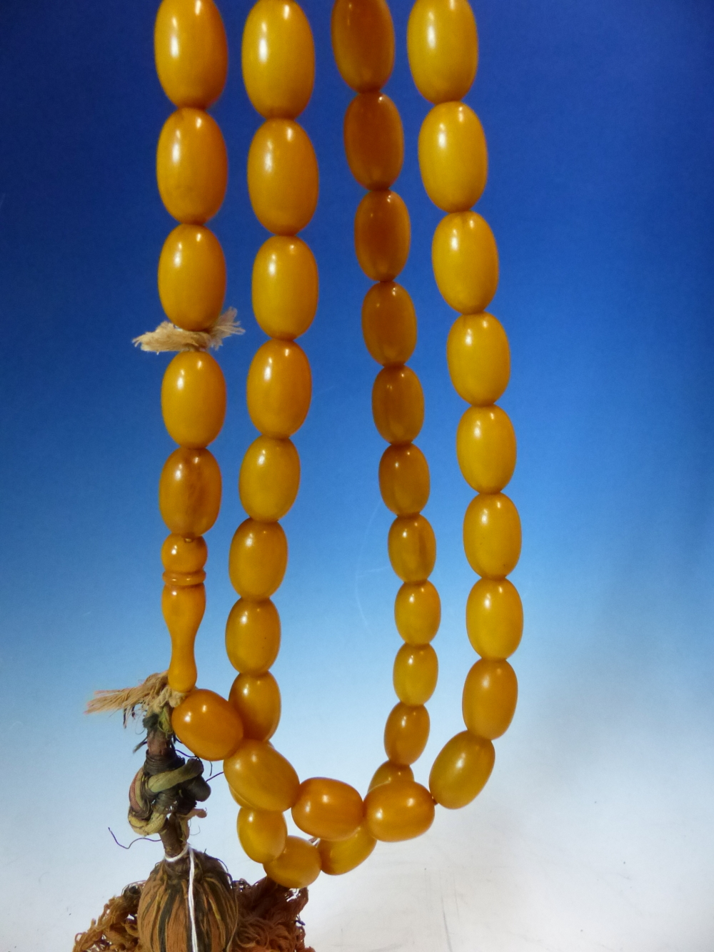 A CONTINUOUS STRING OF 80 UNIFORM OVAL ETHIOPIAN AMBER BEADS WITH KNOT TASSEL PROBABLY FIRST HALF OF - Image 4 of 7