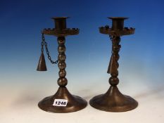 A PAIR OF GOBERG (HUGO BERGER) IRON CANDLESTICKS WITH SNUFFERS CHAINED TO THE CRENELLATED DRIP PANS,