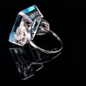 AN AQUAMARINE AND DIAMOND SET ART DECO STYLE RING. CENTERING ON AN EMERALD CUT DARK COLOURED