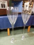 TWO OUTSIZE WINE GLASSES, THE CLEAR TULIP BOWLS ON STEMS AND CIRCULAR FEET. H. 101cms.