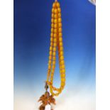 A CONTINUOUS STRING OF 80 UNIFORM OVAL ETHIOPIAN AMBER BEADS WITH KNOT TASSEL PROBABLY FIRST HALF OF
