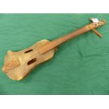 A VINTAGE TRIBAL MADE STRINGED MUSICAL INSTRUMENT , THE BODY OF STRETCHED AND SEWN HIDE WITH CRUDELY