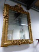 A 19th C. RECTANGULAR MIRROR WITHIN A GILT FRAME WITH RIBBON TIED ESCUTCHEON AT THE CREST AND HUNG