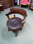 A VICTORIAN DESK CHAIR THE TUB BACK UPHOLSTERED IN LEATHER WITH A GRIFFIN SUPPORTED ARMORIAL ABOVE