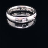 A PLATINUM AND DIAMOND SET BAND. THREE PRINCESS CUT DIAMONDS FLUSH SET IN TO THE PLAIN POLISHED