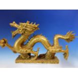 A CHINESE GILT METAL DRAGON STRIDING ACROSS THE RECTANGULAR CLOUD BASE HOLDING A SACRED PEARL. W