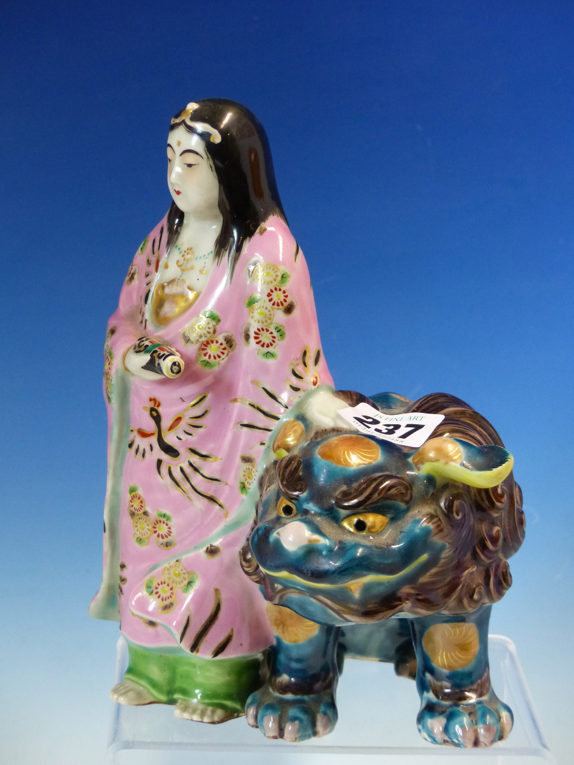 A JAPANESE PORCELAIN FIGURE OF KWANNON STANDING HOLDING A SCROLL, HER PINK ROBE CONTRASTING WITH THE