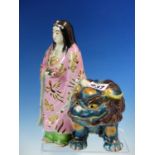 A JAPANESE PORCELAIN FIGURE OF KWANNON STANDING HOLDING A SCROLL, HER PINK ROBE CONTRASTING WITH THE