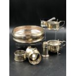 A GROUP OF HALLMARKED SILVER TO INCLUDE A WINE COASTER, THREE NAPKIN RINGS, A PEPPER, TWO MUSTARDS