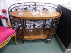 AN IMPRESSIVE WROUGHT IRON AND PINE TWO TIER TROLLEY, THE ELONGATED OVAL SHAPE WORKED WITH FOLIAGE