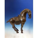 A CHINESE BRONZE HORSE CAST IN THE TANG STYLE WEARING A SADDLE AND BRIDLE. H 32cms.
