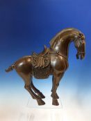 A CHINESE BRONZE HORSE CAST IN THE TANG STYLE WEARING A SADDLE AND BRIDLE. H 32cms.
