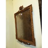 A RECTANGULAR MIRROR WITHIN GADROONED GILT WOOD FRAME SURMOUNTED BY A SWAGGED URN. 76 x 50cms.