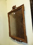 A RECTANGULAR MIRROR WITHIN GADROONED GILT WOOD FRAME SURMOUNTED BY A SWAGGED URN. 76 x 50cms.