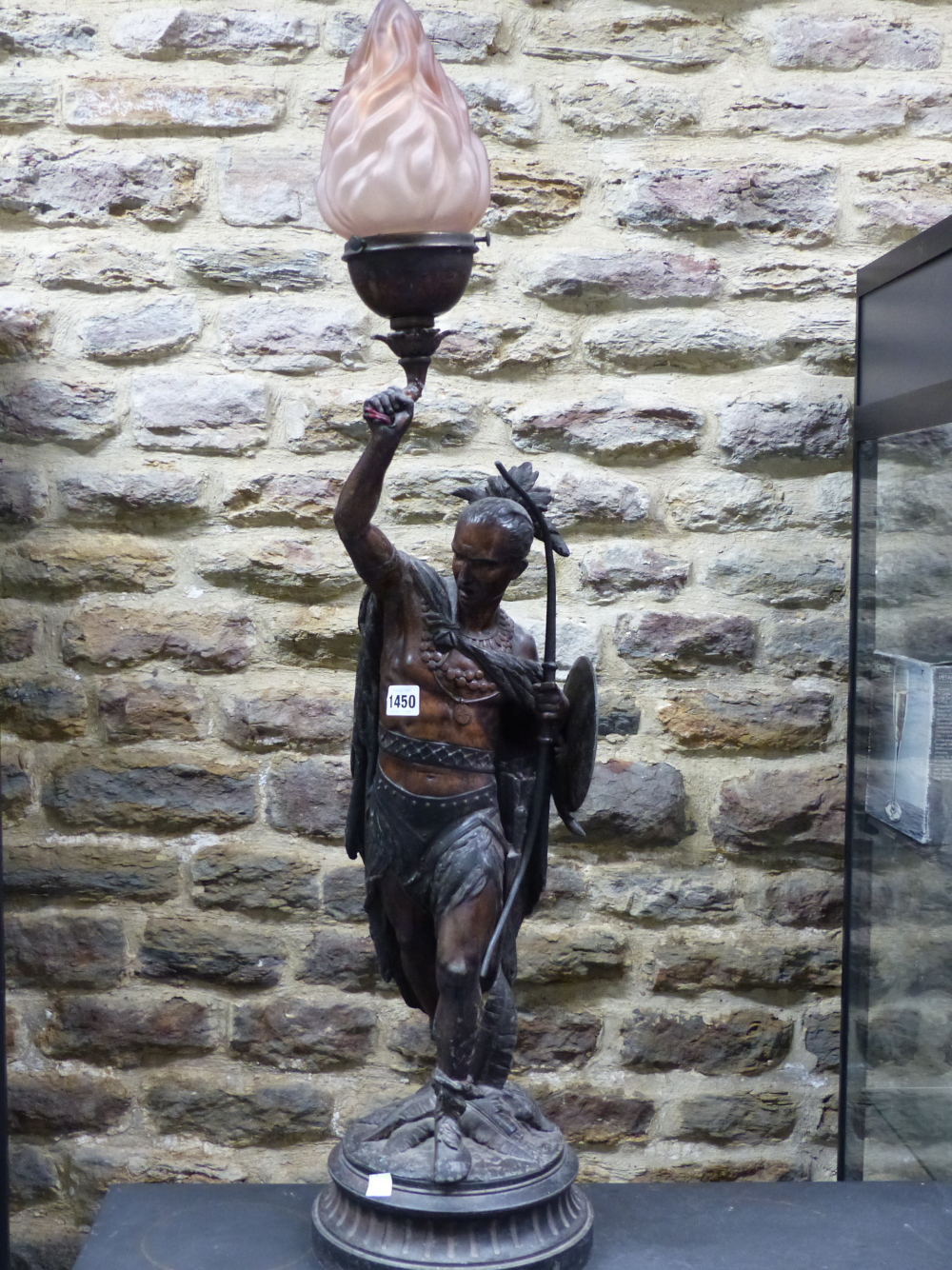 A SPELTER FIGURAL LAMP CAST AS AN AMERICAN INDIAN WITH BOW AND SHIELD IN HIS LEFT HAND WHILE THE