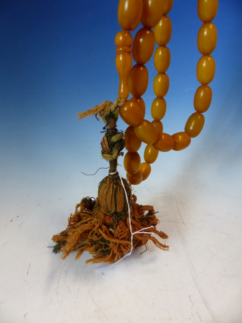 A CONTINUOUS STRING OF 80 UNIFORM OVAL ETHIOPIAN AMBER BEADS WITH KNOT TASSEL PROBABLY FIRST HALF OF - Image 5 of 7