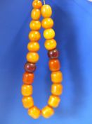 A CONTINUOUS STRING OF 21 ETHIOPIAN AMBER BEADS, PROBABLY FIRST HALF OF THE 20th C. VARYING IN SHAPE