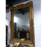 A RECTANGULAR MIRROR IN A GILT FRAME WITH ROCAILLE SHELL CORNERS AND CENTRES TO THE SIDES INCISED