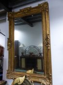 A RECTANGULAR MIRROR IN A GILT FRAME WITH ROCAILLE SHELL CORNERS AND CENTRES TO THE SIDES INCISED