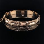 A 9ct GOLD HALLMARKED HINGED BANGLE, WITH DIAMOND CUT DESIGN TO ONE HALF, COMPLETE WITH SAFETY