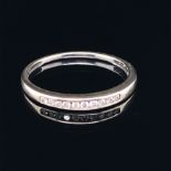 A 9ct WHITE GOLD HALF ETERNITY CHANNEL SET DIAMOND RING. TEN BRILLIANT CUT DIAMONDS IN A PLAIN