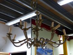 A BRASS TWELVE LIGHT TWO TIER CHANDELIER ON A COLUMN WITH GADROONING, TO THE CEILING FITTING. H