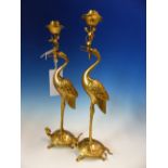 A PAIR OF CHINESE GILT METAL CANDLESTICKS, THE LOTUS NOZZLES SUPPORTED IN THE BEAKS OF CRANES