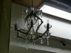 A SIX LIGHT CHANDELIER, THE CLEAR GLASS CLAD ARMS APPLIED WITH FLOWER HEADS AND HUNG WITH PEAR