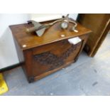 AN EDWARDIAN OAK SIDE CABINET, THE FALL FRONT CARVED WITH CROSSED LEAVES AND OPENING ONTO SHELVES