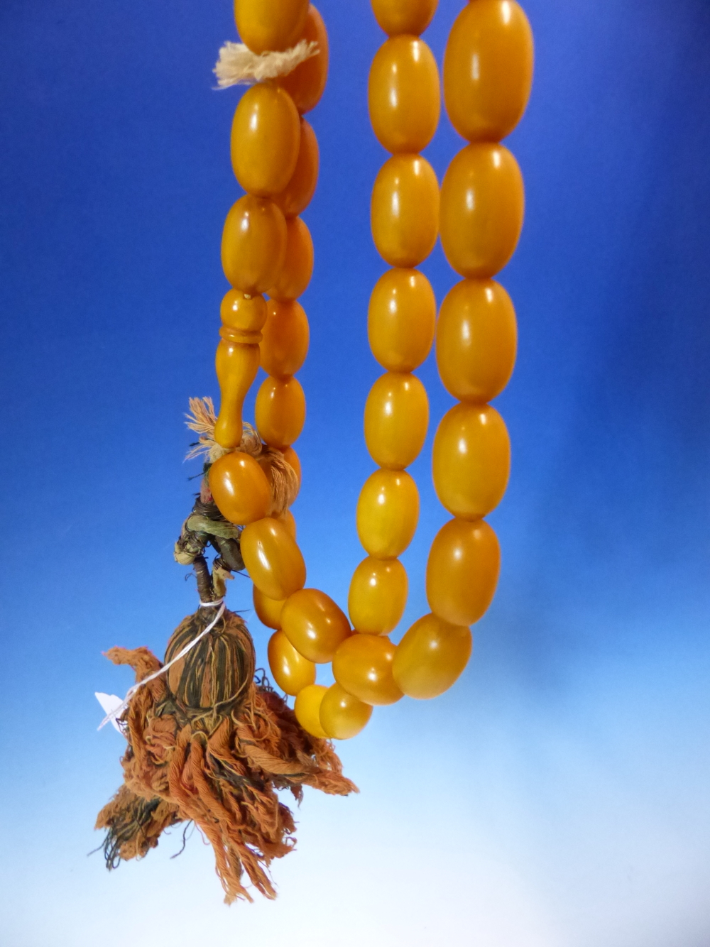 A CONTINUOUS STRING OF 80 UNIFORM OVAL ETHIOPIAN AMBER BEADS WITH KNOT TASSEL PROBABLY FIRST HALF OF - Image 7 of 7